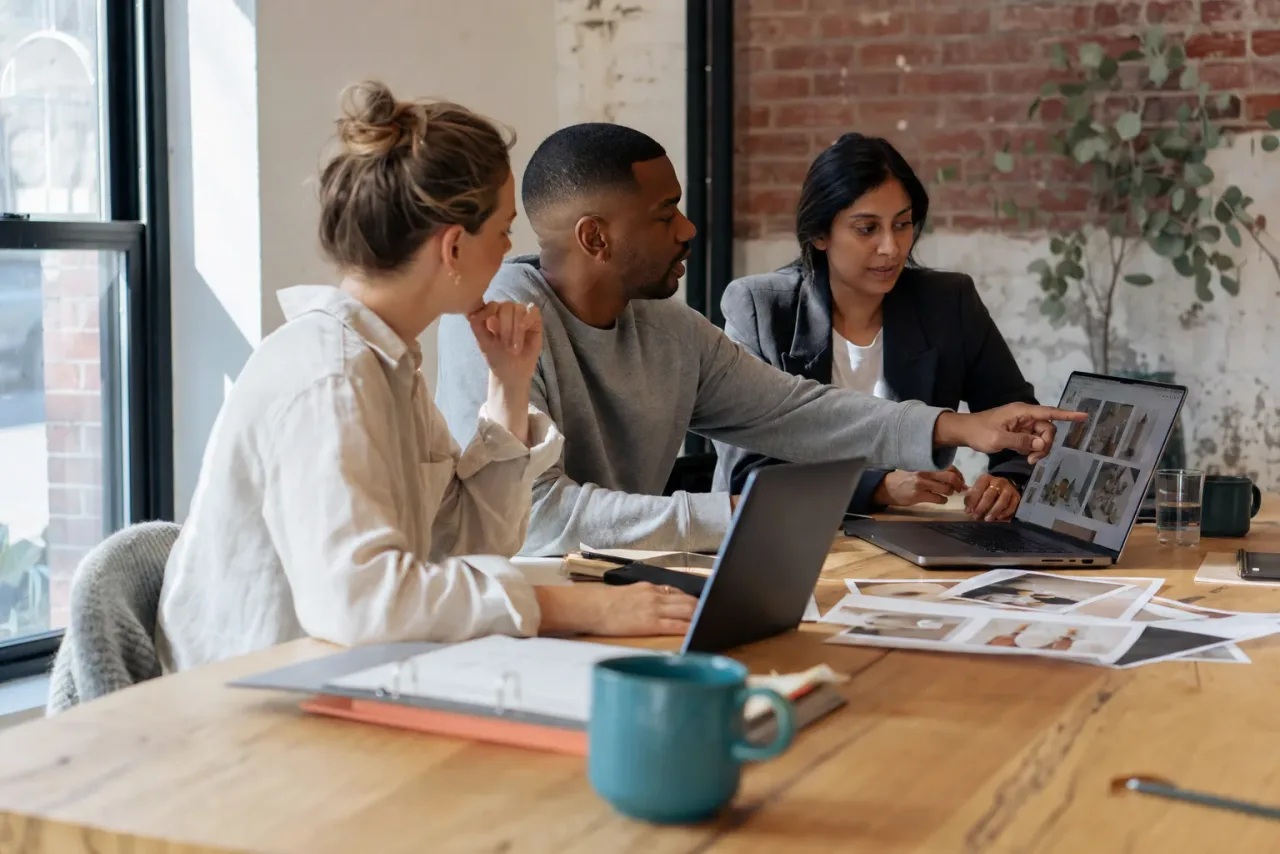 Three retail content team members collaborating on a category-page layout in a studio.